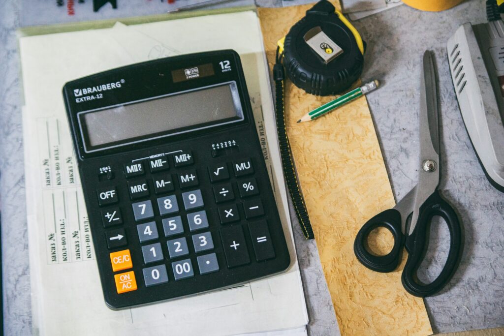 A calculator, scissors and a notebook on a desk